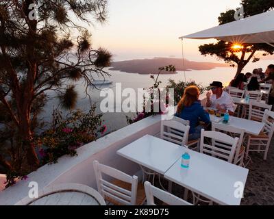 Restaurant avec vue sur la caldeira, dont un bateau de croisière au coucher du soleil à Santorin, une île grecque de la mer Égée. Banque D'Images