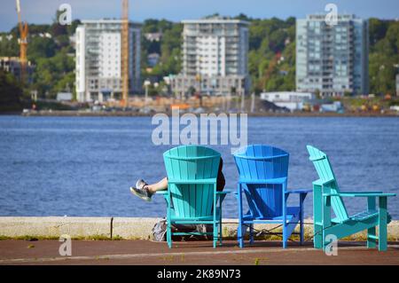 Les gens peuvent se détendre dans des sièges colorés, chaises Adirondack (chaises Muskoka), sur le front de mer urbain de la ville de Halifax, en Nouvelle-Écosse, au Canada atlantique Banque D'Images