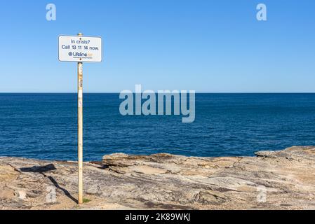 Un panneau pour la ligne d'assistance téléphonique de prévention du suicide Lifeline aux falaises de Shark point à Clovelly, Sydney, Australai Banque D'Images