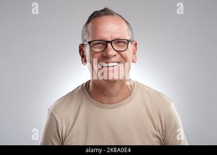 Je pense que je suis spectaculaire. Un beau homme mûr debout seul sur fond gris dans le studio pendant la journée. Banque D'Images