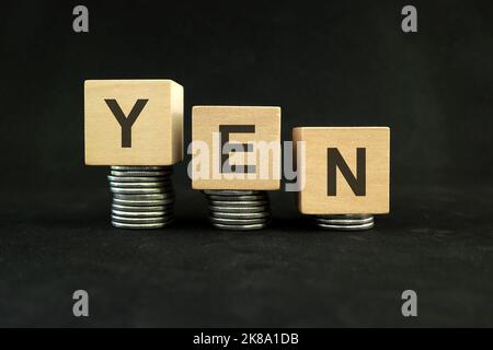 Concept d'affaiblissement du yen japonais, de dépréciation de la valeur et de dévaluation. Diminution de la pile de pièces sur fond noir foncé. Banque D'Images