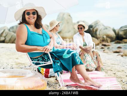 Profitez de la liberté dans un seul morceau et sur la plage. Une femme mûre assise et profiter d'une journée sur la plage avec des amis. Banque D'Images