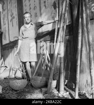 Cecil Beaton - Cecil Beaton (en short et en chemise) avec paniers en osier à côté d'un mur avec des personnages chinois à Puncheng dans le sud-est de la Chine Banque D'Images