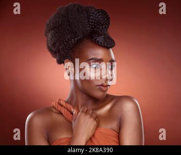 Les accessoires les plus simples parlent le plus fort. Une jeune femme attrayante posant en studio sur un fond rouge. Banque D'Images