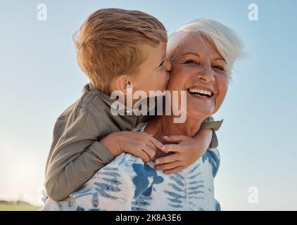 Baiser, enfant et grand-mère dans un parc avec amour, soin et liberté pour le bonheur à la retraite. Senior, sourire et portrait d'une femme avec le hug d'un Banque D'Images