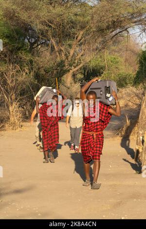 Tarangire, Tanzanie - 12 octobre 2022 : deux porteurs masai transportant des bagages dans un pavillon de savane en Tanzanie. Banque D'Images