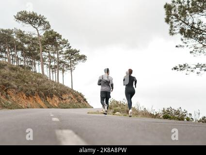 Nous courons pour nourrir nos âmes. Prise de vue en longueur de deux athlètes non reconnaissables se liant pendant une course en plein air. Banque D'Images