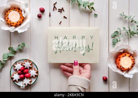 Envoyez les fêtes de fin d'année sur la carte en main. Bougie orange parfumée naturelle, boules de pommandes avec clous de girofle. Brindilles fraîches d'eucalyptus et pain d'épice aromatique Banque D'Images