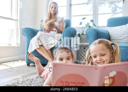 Développement, mère et fille enfants lisant avec livre, sourire et heureux sur le sol, ensemble et à la maison. Femme, femme et fille qui font la garde d'enfants Banque D'Images