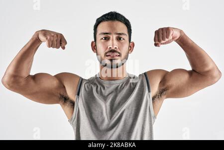Tout est gagné, pas donné. Portrait en studio d'un jeune homme musclé qui plie ses biceps sur un fond blanc. Banque D'Images