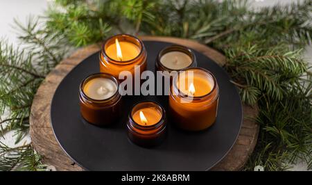 Les bougies de soja brûlent dans des pots en verre. Confort à la maison. Bougie dans un pot brun. Parfum et lumière. Bougie parfumée faite à la main. Aromathérapie. Arbre de Noël et ambiance d'hiver. Décoration chaleureuse. Décoration de fête Banque D'Images