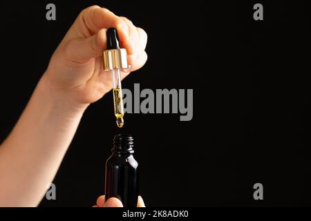 Huile naturelle pour le soin des cils, sourcils, peau du visage goutte dans un pot en verre de pipette Banque D'Images