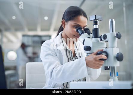 La science ouvre la porte à un avenir meilleur. Un jeune scientifique utilisant un microscope tout en effectuant des recherches dans un laboratoire. Banque D'Images