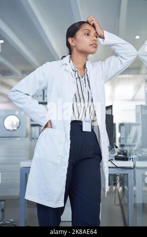 Prendre sur le monde de la santé prend son tribut. Un jeune scientifique regardant stressé tout en menant des recherches dans un laboratoire. Banque D'Images