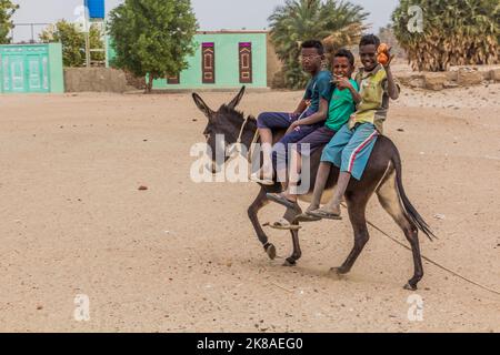 ABRI, SOUDAN - 26 FÉVRIER 2019 : des garçons de la région à cheval sur l'âne près d'abri, au Soudan Banque D'Images