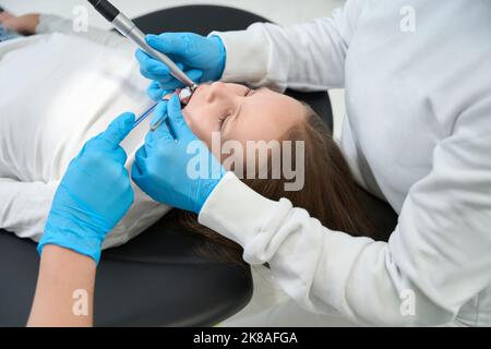 Dentiste pédiatrique traitant des caries chez l'enfant de la préadolescence avec l'aide d'un assistant Banque D'Images