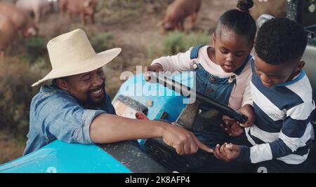 Le monde réel est plein de leçons de la vie réelle. Un homme mûr aidant son adorable fils et sa fille à monter un tracteur sur une ferme. Banque D'Images