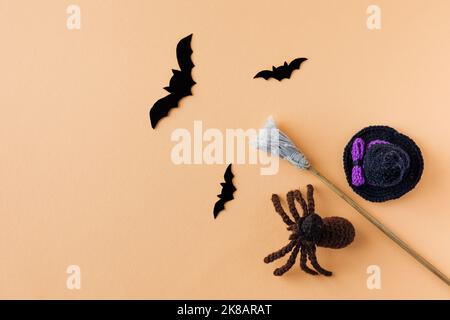 Concept Halloween. Un chapeau noir, un balai de sorcière et des chauves-souris noires et une araignée sur fond orange Banque D'Images