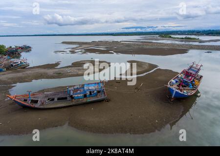 Aceh, Indonésie. 22 octobre 2022. Un chantier naval particulier pour les bateaux de pêche dans la zone de l'estuaire du village de Pusong, ville de Lhokseumawe. Les bateaux de pêche traditionnels sont construits en utilisant le bois comme matériau primaire. Il n'y a pas d'activité de travailleur, ils sont en congé le week-end. Deux bateaux endommagés doivent être réparés et amarrés dans le sable par des cordes de verrouillage. Banque D'Images