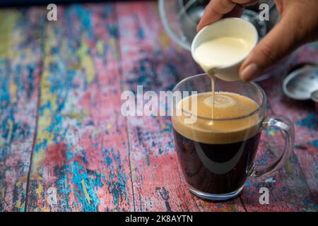 Americano avec la crème versée dans la boisson Banque D'Images