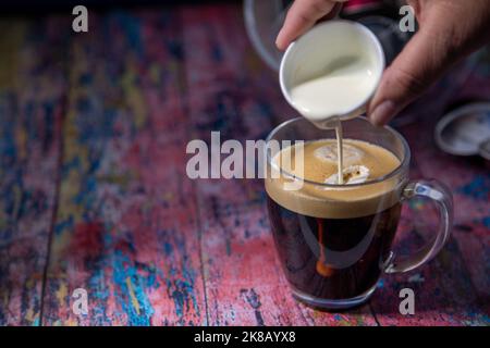 Americano avec la crème versée dans la boisson Banque D'Images