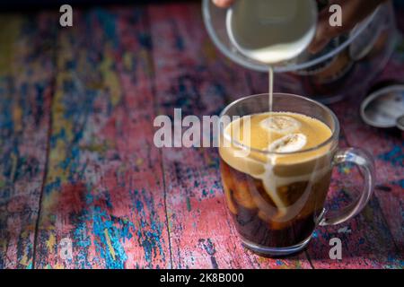 Americano avec la crème versée dans la boisson Banque D'Images