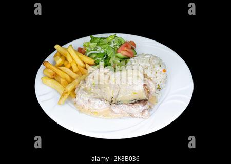 Poulet au citron avec riz, salade et frites dans une assiette blanche sur fond noir Banque D'Images