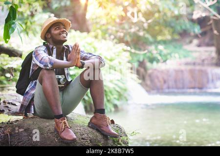 Le touriste de trekking africain prie Dieu pour remercier les bonnes choses dans sa vie. Concept de foi, de religion et de bonne vie. Banque D'Images