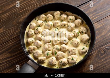 Boulettes de viande suédoises à la sauce blanche crémeuse dans une casserole sur fond de bois. Vue rapprochée Banque D'Images