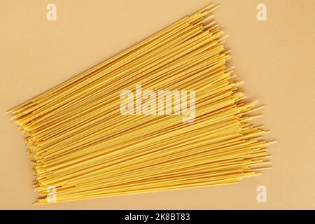 Séchez les pâtes spaghetti sur un fond beige. Gros plan sur les pâtes jaunes italiennes. Vue de dessus Banque D'Images