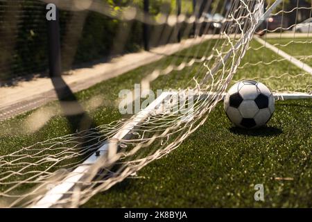 ballon de football blanc et noir sur fond d'herbe verte et de stade. idée de paris sportifs. Banque D'Images