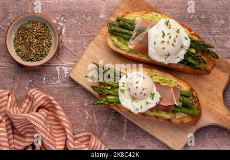 Photographie alimentaire de la bruschetta, toasts aux œufs pochés, asperges, prosciutto, avocat Banque D'Images