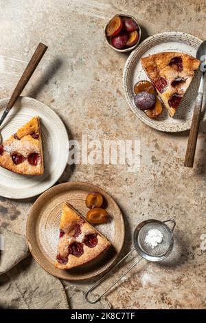 Morceaux de la tarte New York Times Plum Cake avec sucre en poudre sur fond brun texturé, vue de dessus, plat. Orientation verticale Banque D'Images