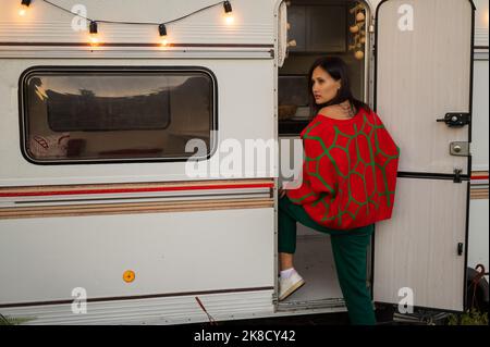 Une femme caucasienne en pull tricoté rouge surdimensionné voyage à motorhome en automne. Banque D'Images
