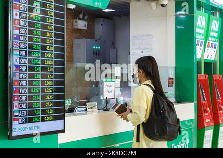 Bangkok, Thaïlande - 26 octobre 2022 : voyageur asiatique au guichet de change bancaire de l'aéroport de suvarnabhumi avec affichage du taux de change Banque D'Images