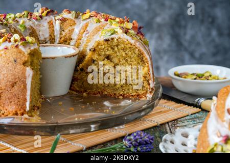 Gâteau parfumé d'amour perse décoré avec du glaçage à la vanille, des pistaches écrasées et des pétales de rose séchés Banque D'Images