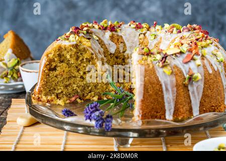 Gâteau parfumé d'amour perse décoré avec du glaçage à la vanille, des pistaches écrasées et des pétales de rose séchés Banque D'Images