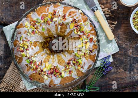 Gâteau parfumé d'amour perse décoré avec du glaçage à la vanille, des pistaches écrasées et des pétales de rose séchés Banque D'Images