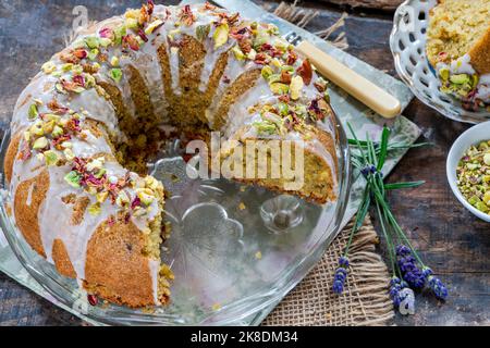 Gâteau parfumé d'amour perse décoré avec du glaçage à la vanille, des pistaches écrasées et des pétales de rose séchés Banque D'Images