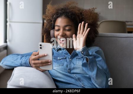 Une fille africaine dans un casque accueille un ami lancer un vidéocall à l'aide d'un smartphone Banque D'Images