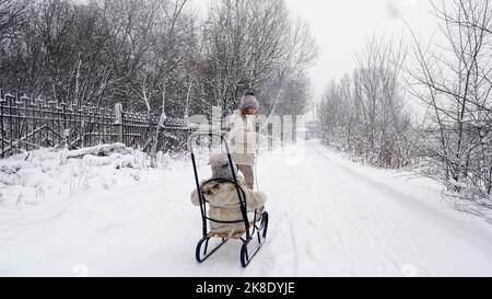 en hiver, en famille, en plein air. Les enfants sont heureux, rires et ludiques. Ils s'amusent sur une route enneigée, en forêt ou en chute de neige. Les enfants s'amusent par une journée hivernale enneigée. Ralenti. Photo de haute qualité Banque D'Images