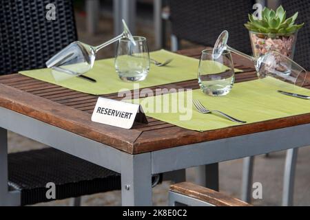 Affiche de table réservée au restaurant avec verres à vin prêts pour une fête. Panneau en fer sur une table en bois avec le mot « Reserviert » sur l'allemand Banque D'Images