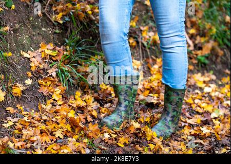 Femme portant des bottes de camouflage wellington marchant à travers l'automne quitte l'Angleterre Royaume-Uni Banque D'Images