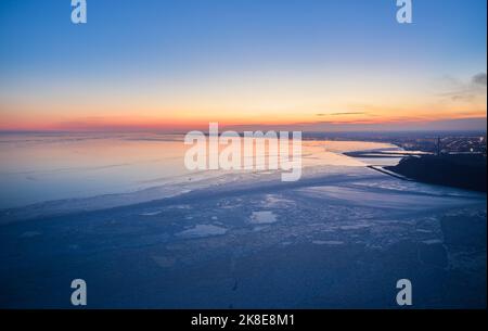 Vue aérienne du coucher de soleil sur la mer gelée. Paysage hivernal sur la mer au crépuscule. Vue depuis le dessus de la fonte de glace dans l'océan au lever du soleil avec horizon Banque D'Images