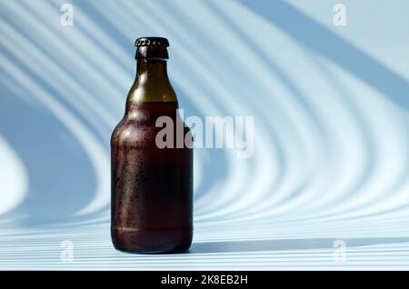 Vue de dessus de la bouteille de bière brune en verre, verre de bière sur fond bleu gros plan. Mode de vie de la nourriture. Production de boissons alcoolisées. Copier l'espace, maquette. Banque D'Images