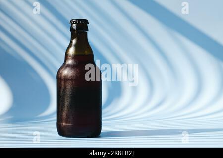 Vue de dessus de la bouteille de bière brune en verre, verre de bière sur fond bleu gros plan. Mode de vie de la nourriture. Production de boissons alcoolisées. Copier l'espace, maquette. Banque D'Images