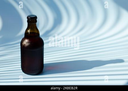 Vue de dessus de la bouteille de bière brune en verre, verre de bière sur fond bleu gros plan. Mode de vie de la nourriture. Production de boissons alcoolisées. Copier l'espace, maquette. Banque D'Images