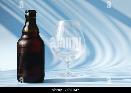 Vue de dessus de la bouteille de bière brune en verre, verre de bière sur fond bleu gros plan. Mode de vie de la nourriture. Production de boissons alcoolisées. Copier l'espace, maquette. Banque D'Images