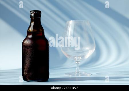 Vue de dessus de la bouteille de bière brune en verre, verre de bière sur fond bleu gros plan. Mode de vie de la nourriture. Production de boissons alcoolisées. Copier l'espace, maquette. Banque D'Images