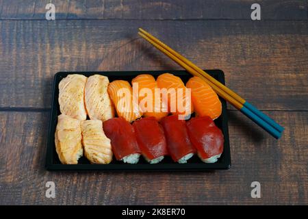 Boîte de sushi avec sushi nigiri : saké d'Aburi, saké et maguro (saumon et thon). Banque D'Images